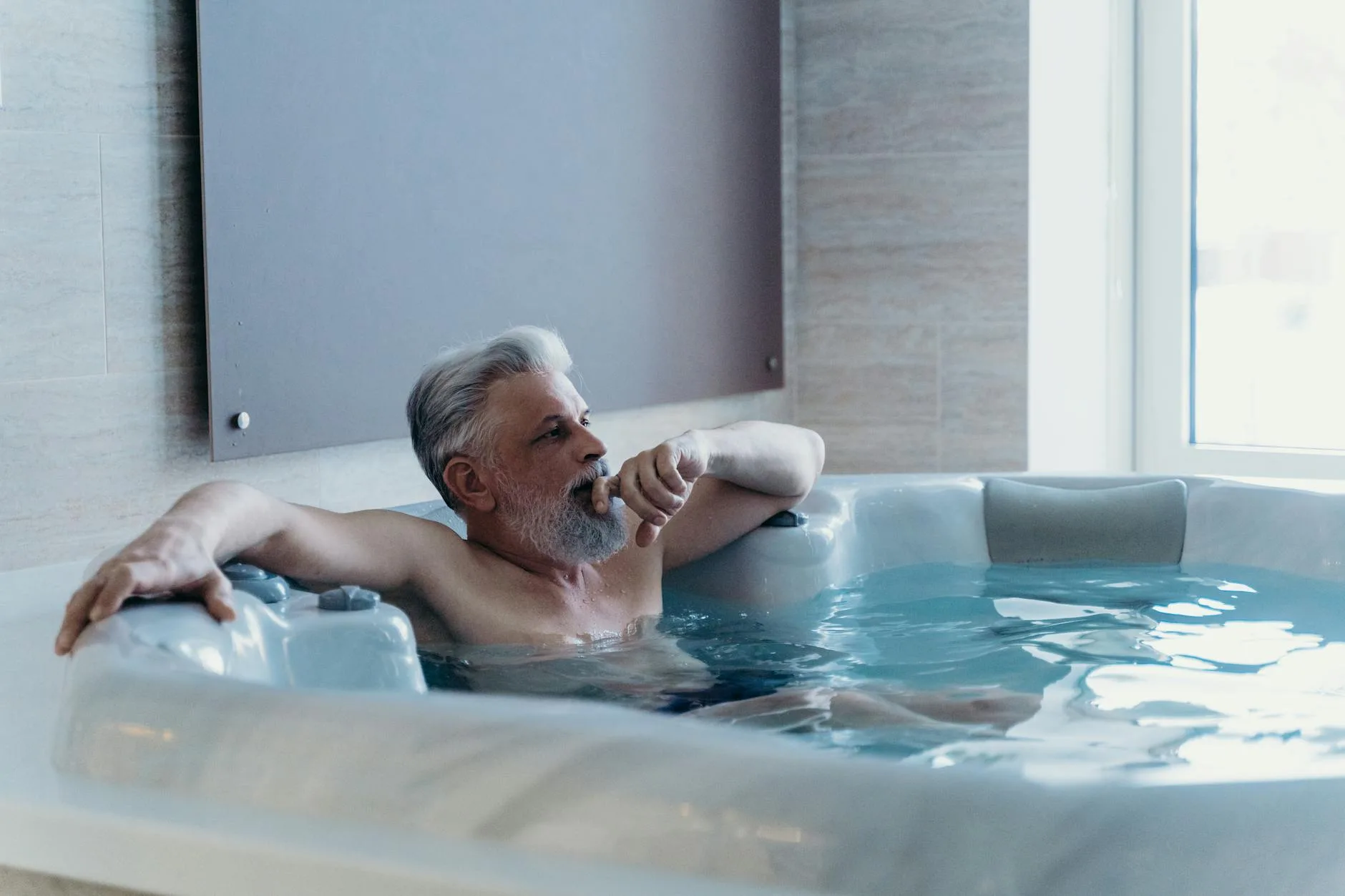 Person relaxing in a hot tub in a garden during evening