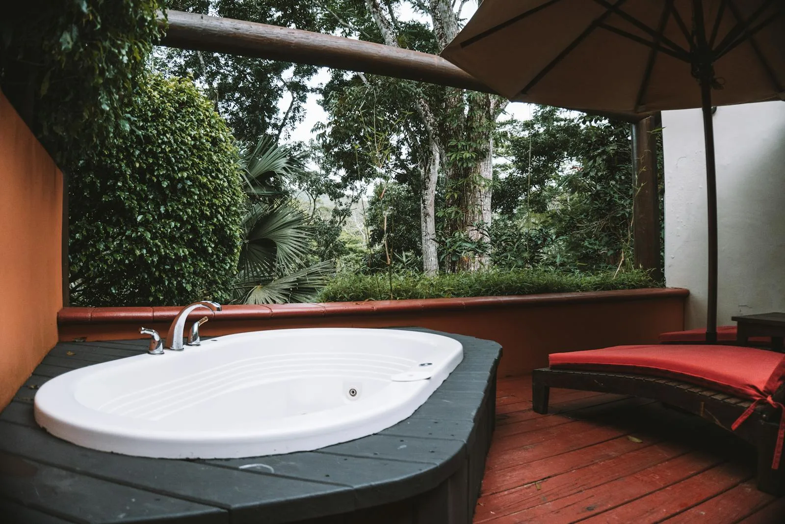 Hot tub on a raised terrace with steps surrounded by garden greenery